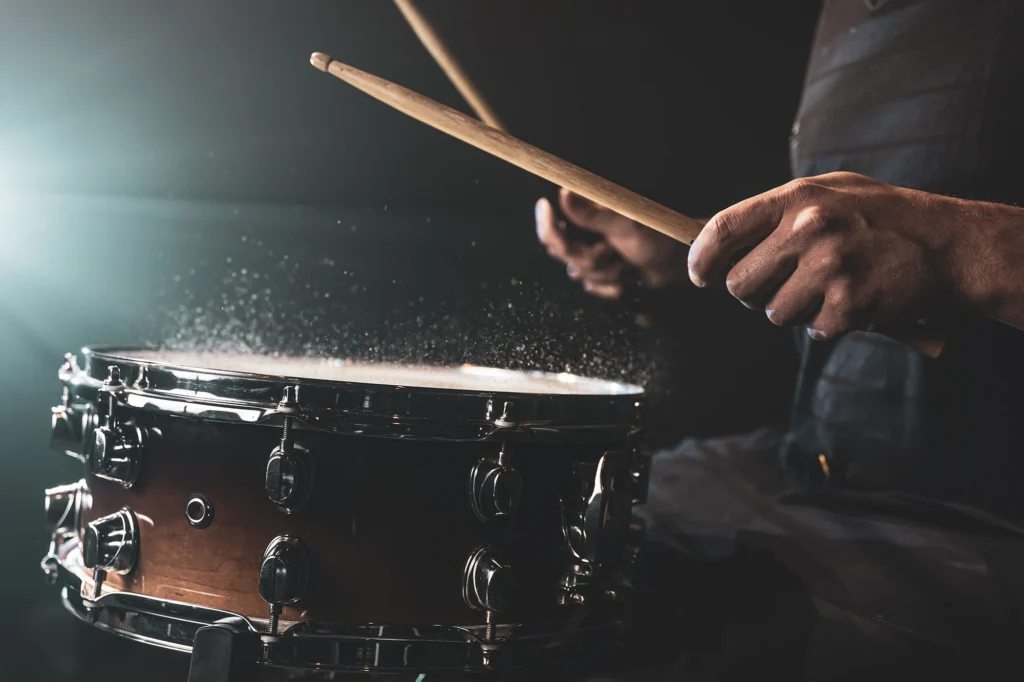 Foto de cerca que muestra un baterista tocando la batería y salpicando agua al golpear