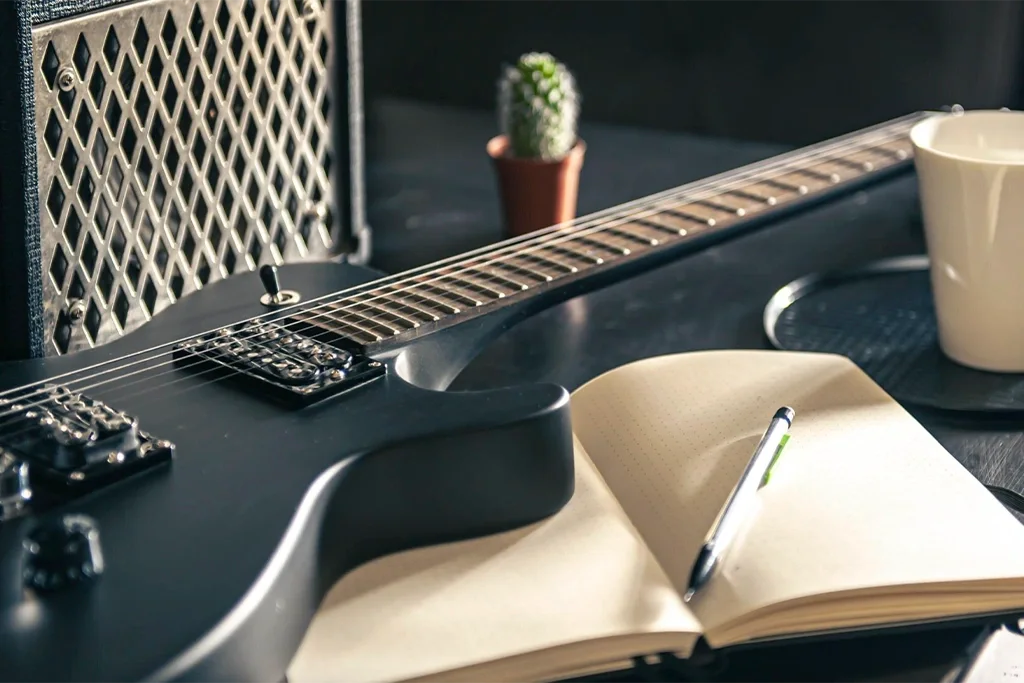 Foto de guitarra en una mesa con una libreta